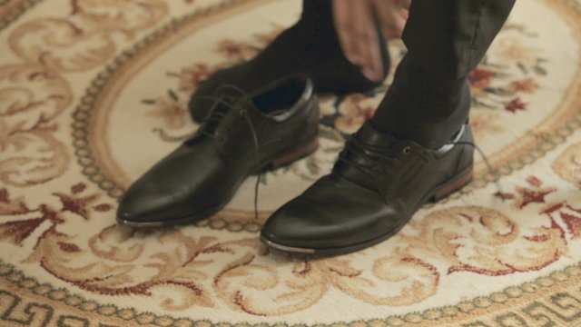 Groom puts shoes on while sitting on a chair