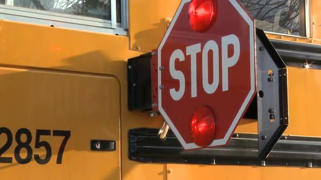 Two takes of the stop sign on a school bus swinging out to signal drivers to stop for school children.