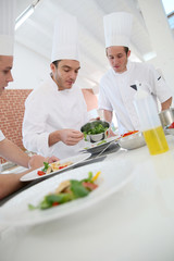 Chef training students in restaurant kitchen