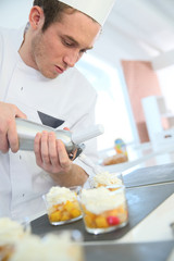 Pastry cook spreading whipped cream on dessert