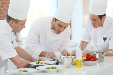 Chef training students in restaurant kitchen - obrazy, fototapety, plakaty