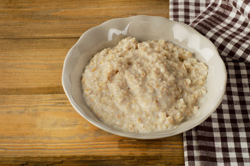 Bowl of oatmeal on old wooden table. Healthy breakfast