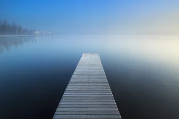 Poster Empty jetty in a foggy lake during sunrise. © sanderstock