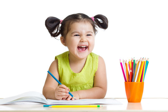 Adorable child drawing with colorful crayons and smiling