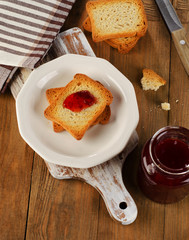 Strawberry jam topping a slice of toast on  plate.