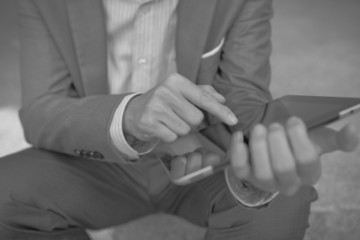 Obraz premium Businessman using electronic tablet pc. He is sitting on a stair