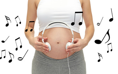 close up of pregnant woman and headphones on tummy