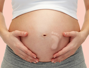 close up of pregnant woman touching her bare tummy