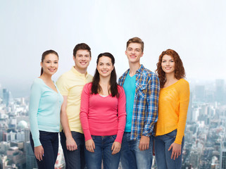 group of smiling teenagers over city background