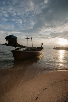 Boat on the beach at sunrise in tide time.