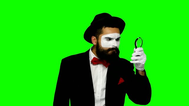 Man mime looks uses magnifier on green screen
