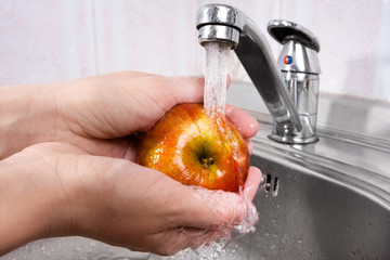 hands washing apple under water
