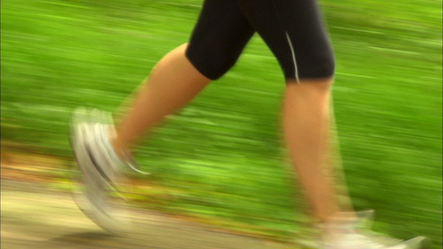 Close shot of woman's legs running down country lane