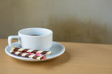 striped wafer rolls filled and coffee on wooden table