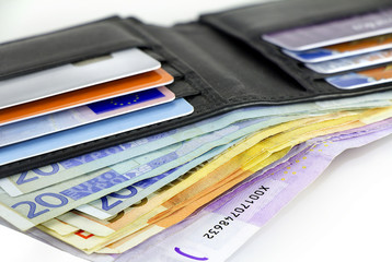 A bundle of Euro banknotes and credit cards in a black leather wallet