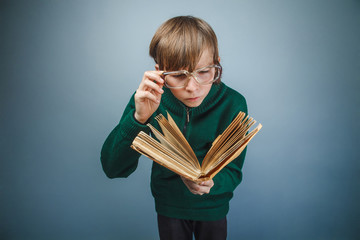 European-looking boy of ten years in glasses reading a book on