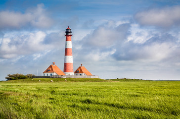 Fototapeta na wymiar Traditional lighthouse at North Sea with blue sky and clouds