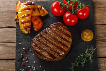 grilled beef steak with vegetables on a wooden surface