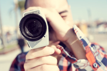 young man filming with a Super 8 camera - Powered by Adobe