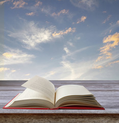 Open book on table in front of sky
