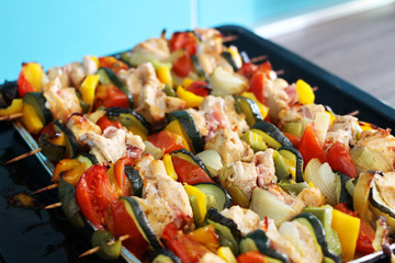 Chicken skewers with bacon and vegetables on a tray.