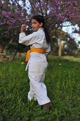 Young girl in kimono w yellow belt exercising karate.