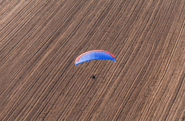 aerial view of paramotor flying over the harvest field