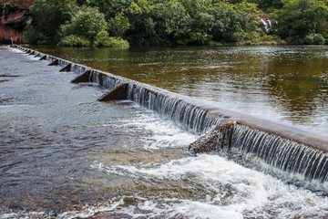 Foaming water coming over a small waterfall from a dam.