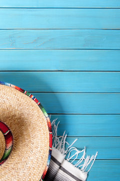 Mexican background with sombrero straw hat and traditional serape rug or blanket on old blue planked wood Mexico holiday vacation cinco de mayo photo vertical