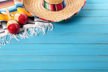 Mexican background with sombrero straw hat maracas and traditional serape rug or blanket on old planked blue wood Mexico holiday vacation cinco de mayo photo 