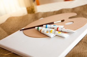 paint tubes, pallet and brush lying on table at living room
