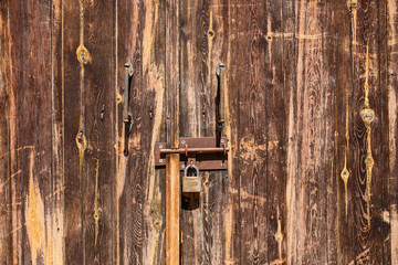 Old wooden door with scratches texture and a hanging lock.