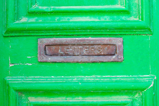 A letter box in a green old wooden door