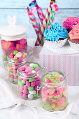 Multicolor candies in glass jars and cupcakes
