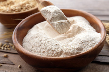 Flour and grains in bowls on wooden background