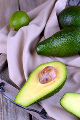 Avocado with limes on tray on wooden background