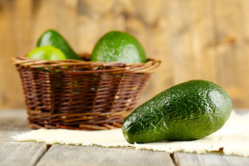 Avocado with limes in basket on wooden background
