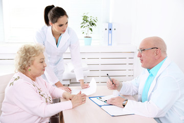 Happy doctors and patient in hospital clinic