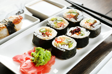 Vegetarian sushi rolls on plate, on wooden background