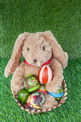 Rabbit, sit and holding colorful eggs in basket on grass for hap