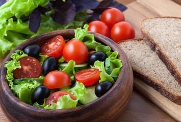 Healthy vegetarian salad with tomato and olives on rustic backgr