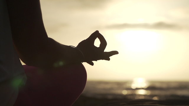 Close up hand of a woman meditating in a yoga pose at sunset