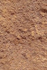 Closeup of a rough concrete wall painted ocher