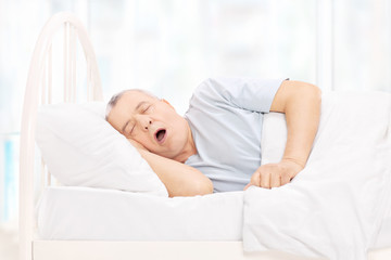Fototapeta na wymiar Mature man sleeping in a comfortable bed