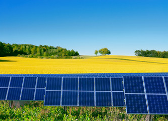 Solar power cells with a rapeseed field  as a backgrop