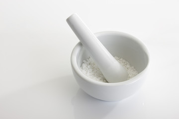 Weisser Mörser mit Stössel und grobem Meersalz