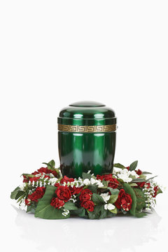 Grüne Urne aus Metall mit Blumenkranz Stock-Foto | Adobe Stock