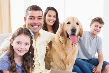 Smiling family sitting with Golden Retriever on sofa