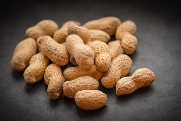 Natural looking roasted peanuts on a dark background.