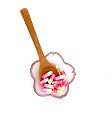 white and pink capsule in bowl with wooden spoon